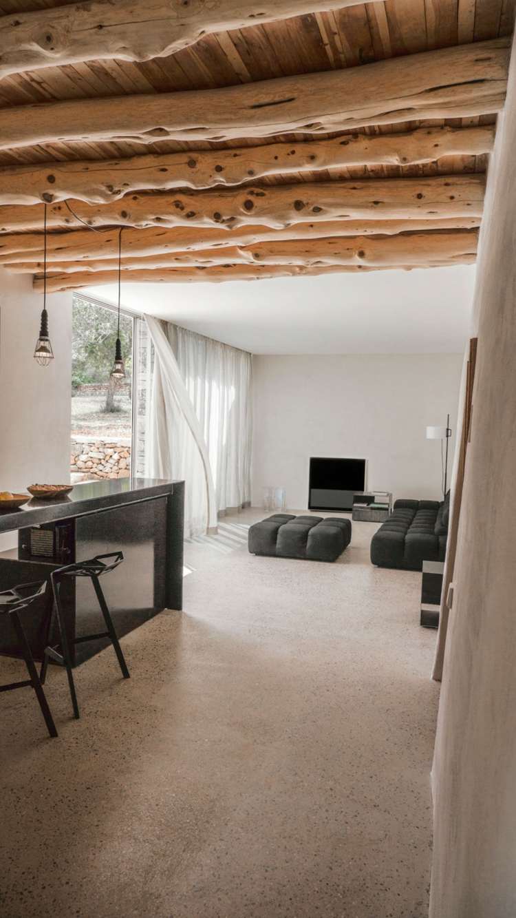 Mur en pierre apparente, mobilier en bois et plafond en poutres