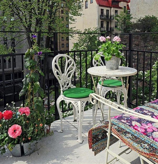table-chaises-blanches-métal-coussins-verts-fleurs-balcon