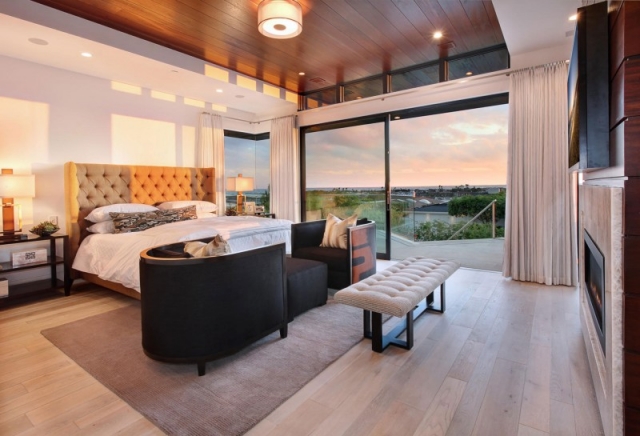 chambre-coucher-luxe-baie-coulissante-plafond-bois-couleurs-chaleureuses-tête-lit-capitonnée
