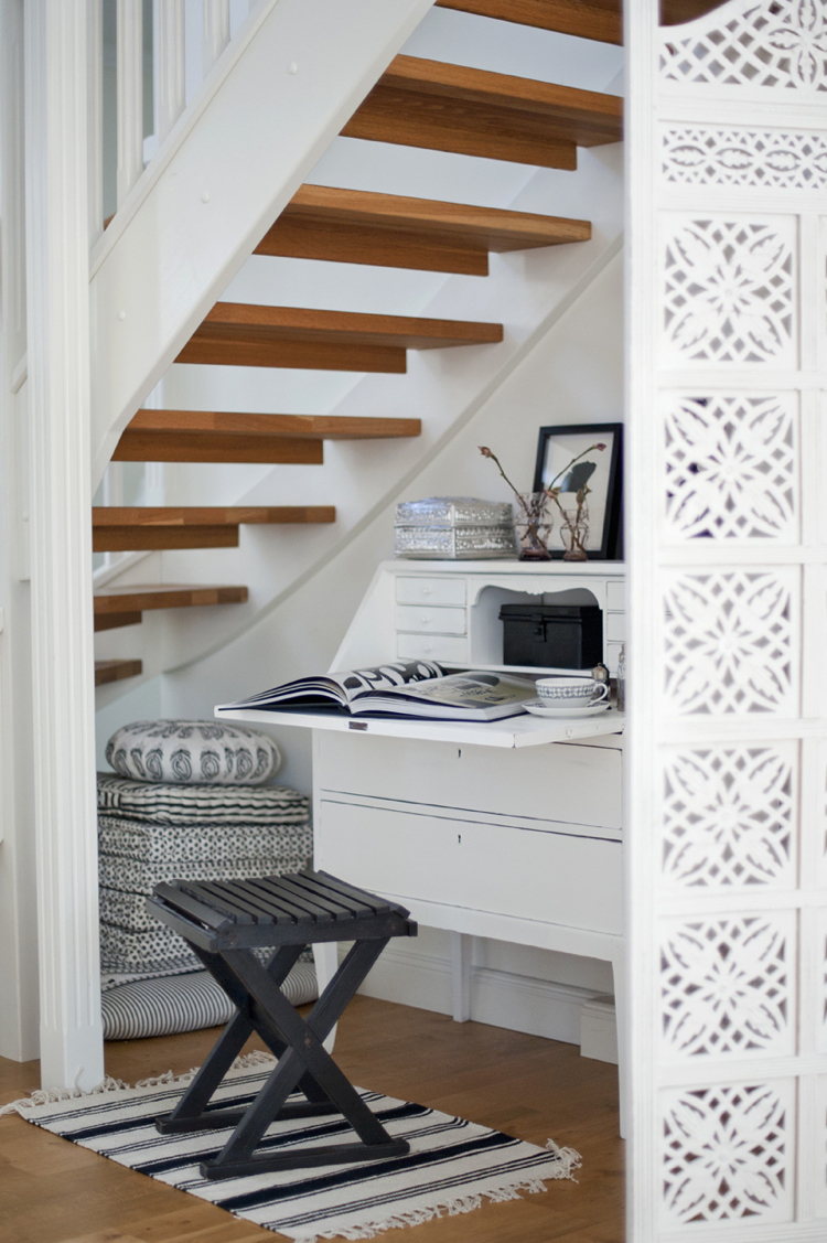 Workstation in niche below stairs - black stool on rug in front of white bureau