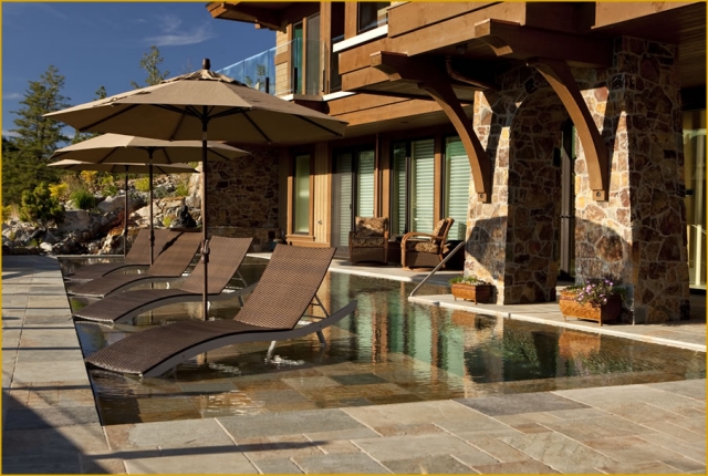 piscine de jardin chaises-longues-bruns-parasols-mur-revêtement-pierre