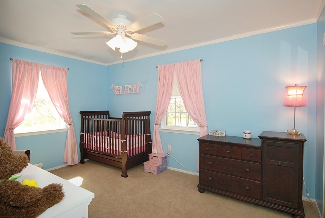 chambre-bébé-déco-mobilier-murs-bleu-pâle-accents-rideaux-lampe-rose-mobilier-bois-tons-foncé chambre bébé