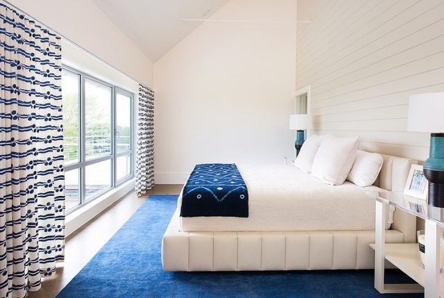 chambre-coucher-moderne-mur-aspect-bois-blanc-lit-élégant-literie-blanche-couverture-bleue-tapis-bleu-rideaux-blancs-motifs-noirs chambre à coucher contemporaine