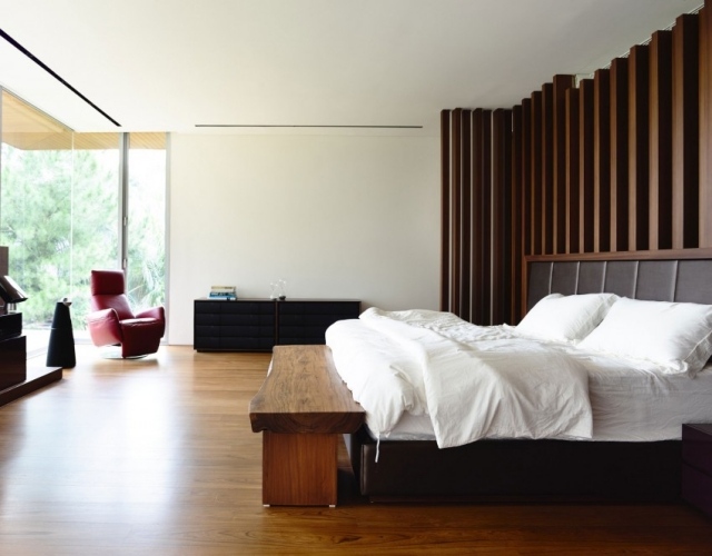 chambre-coucher-moderne-murs-aspect-bois-banc-bois-grand-lit-fauteuil-cuir-bordeaux chambre à coucher contemporaine
