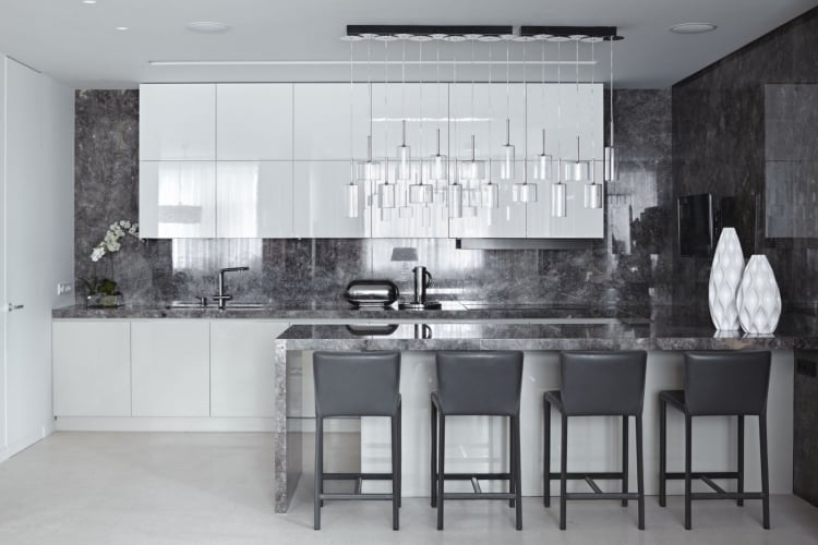 cuisine-moderne-carrelage-mural-gris-aspect-marbre-îlot-moderne-blanc-gris-chaises-cuir-noir