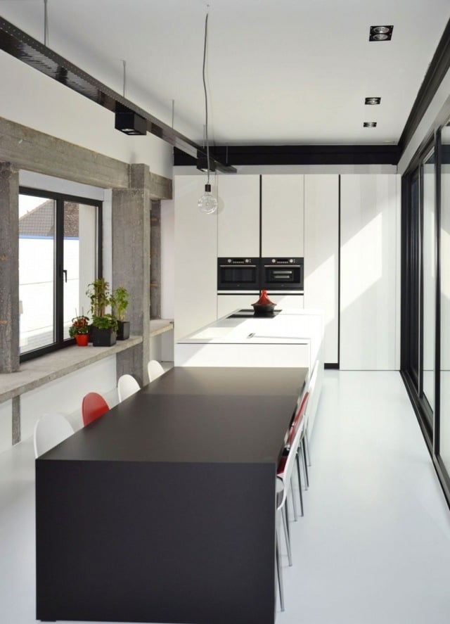 cuisine-moderne-îlot-noir-chaises-blanc-rouge-murs-aspect-béton-armoires-blanches
