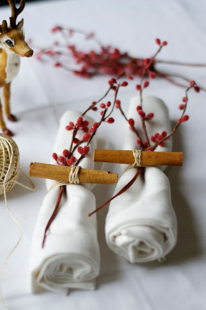 décoration-table-Noël-serviettes-blanches-pliées-rond-serviette-bâton-cannelle-branches-baies-rouges