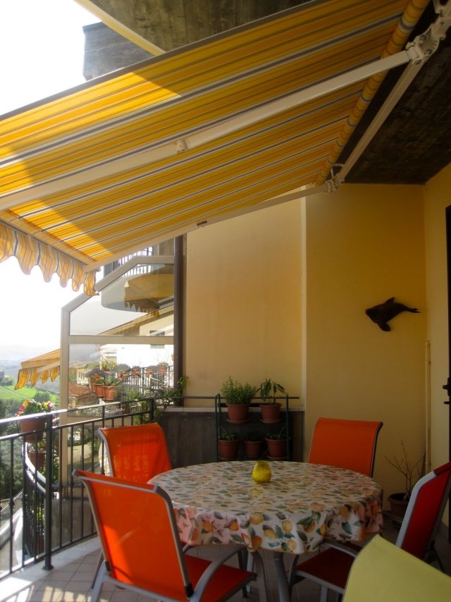 aménagement-balcon-auvent-retractable-table-ronde-chaises-oranges