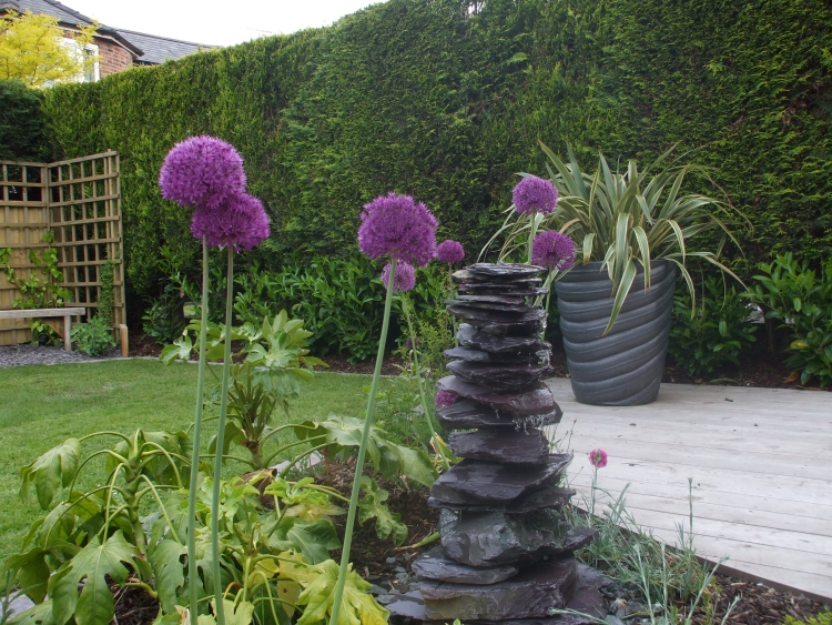 fontaine de jardin tour pierres fleurs violettes
