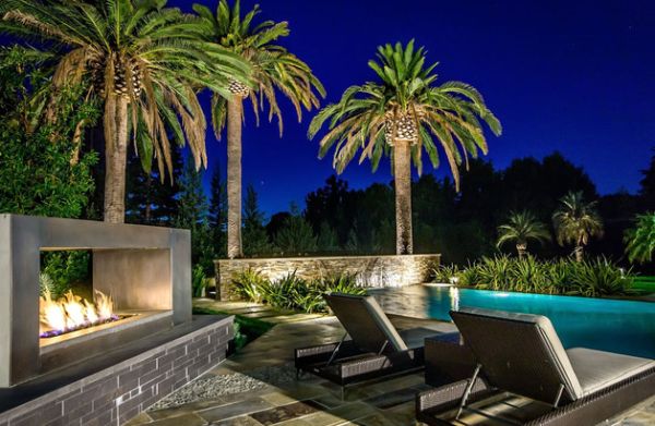 foyer-extérieur-cheminée-moderne-piscine-palmiers-chaises-longues