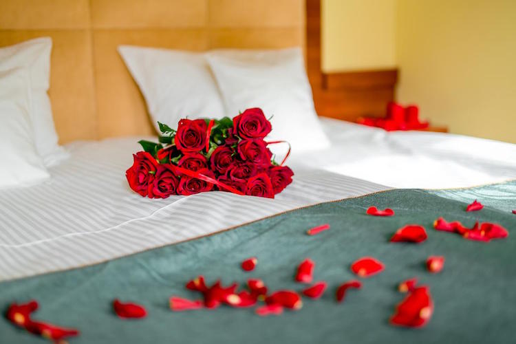 bouquet de roses rouges et petales de roses sur le lit romantique