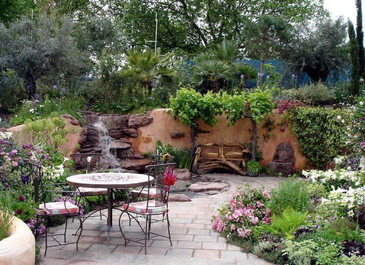 jardin-méditerranéen-plantes-vertes-fleurs-table-ronde-cascade-rochers