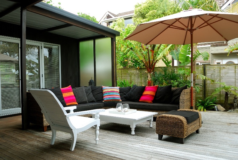 terrasse-extérieur-lit-jour-rotin-canapé-coussins-rouges-parasol