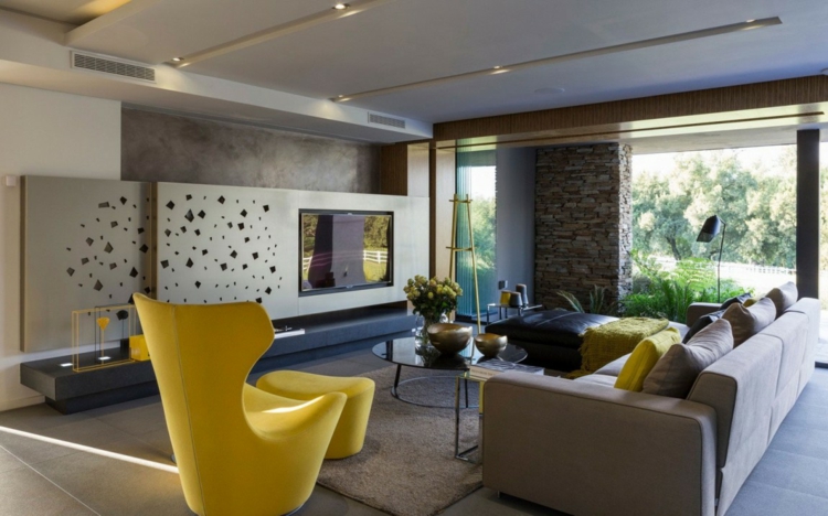 interieur-materiaux-naturels-mur-pierre-béton-salle-séjour-canapé-gris-fauteuil-jaune