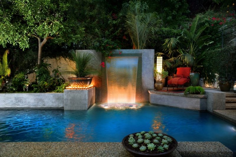 piscine-exterieur-cascade-moderne-éclairage-led-plantes-vertes-fauteuil piscine extérieur