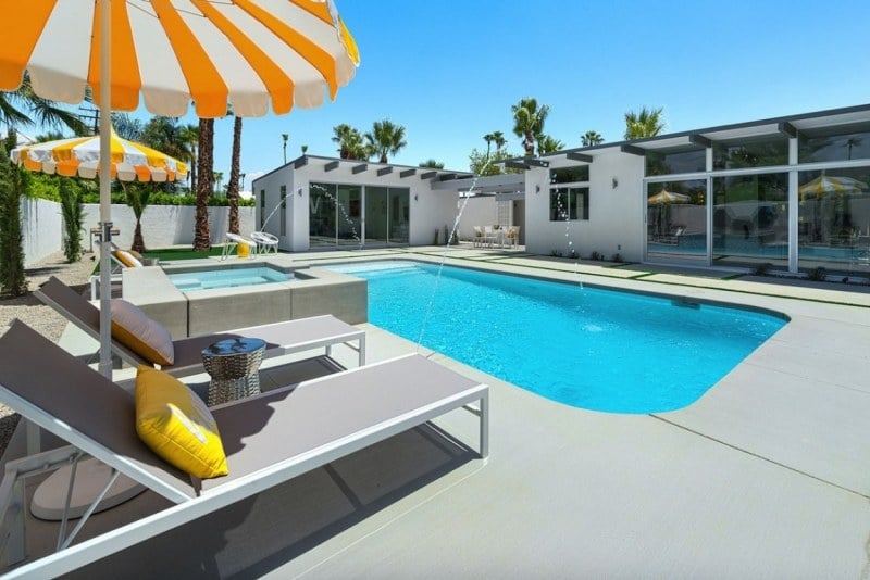 piscine-exterieur-élégante-chaises-longues-grises-parasols-blanc-orange-dalles-béton piscine extérieur