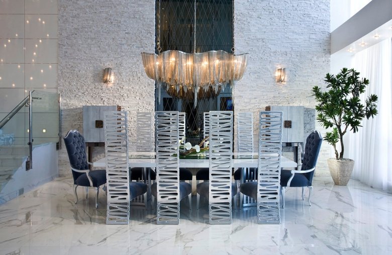suspension-salle-manger-chaînettes-métaliques-sol-marbre-mur-pierre-chaises-dossiers-métalliques suspension salle à manger