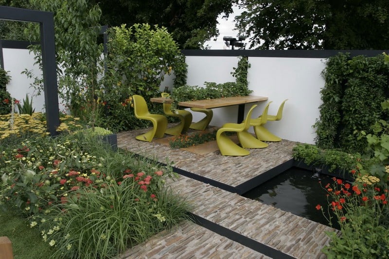amenagement-petit-jardin-revetement-sol-pierre-naturelle-étang-table-bois-chaises-panton