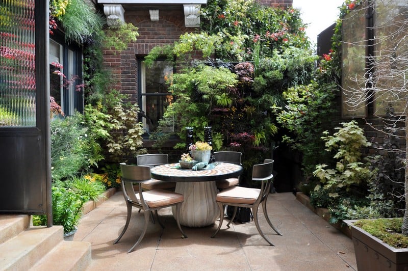 amenagement-petit-jardin-table-bois-ronde-chaises-végétation-opulente