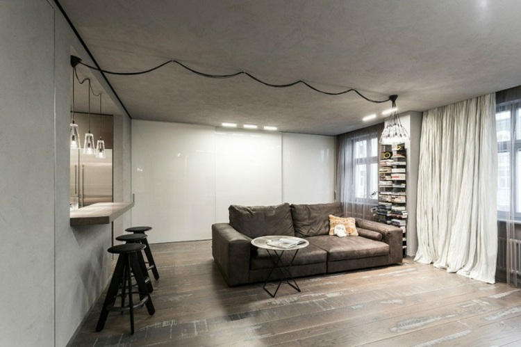 amenagement-studio-2-canapé-cuir-gris-foncé-plafond-béton-tabourets-bar-noires-cuisine
