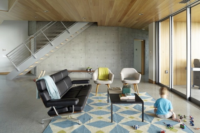 design-mural-salon-mur-béton-plafond-bois-tapis-motifs-bleu-jaune-canapé-noir design mural