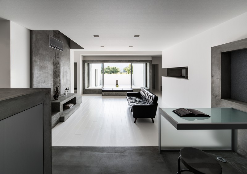 interieur-minimaliste-salle-séjour-canapé-capitonné-noir-mur-accent-béton
