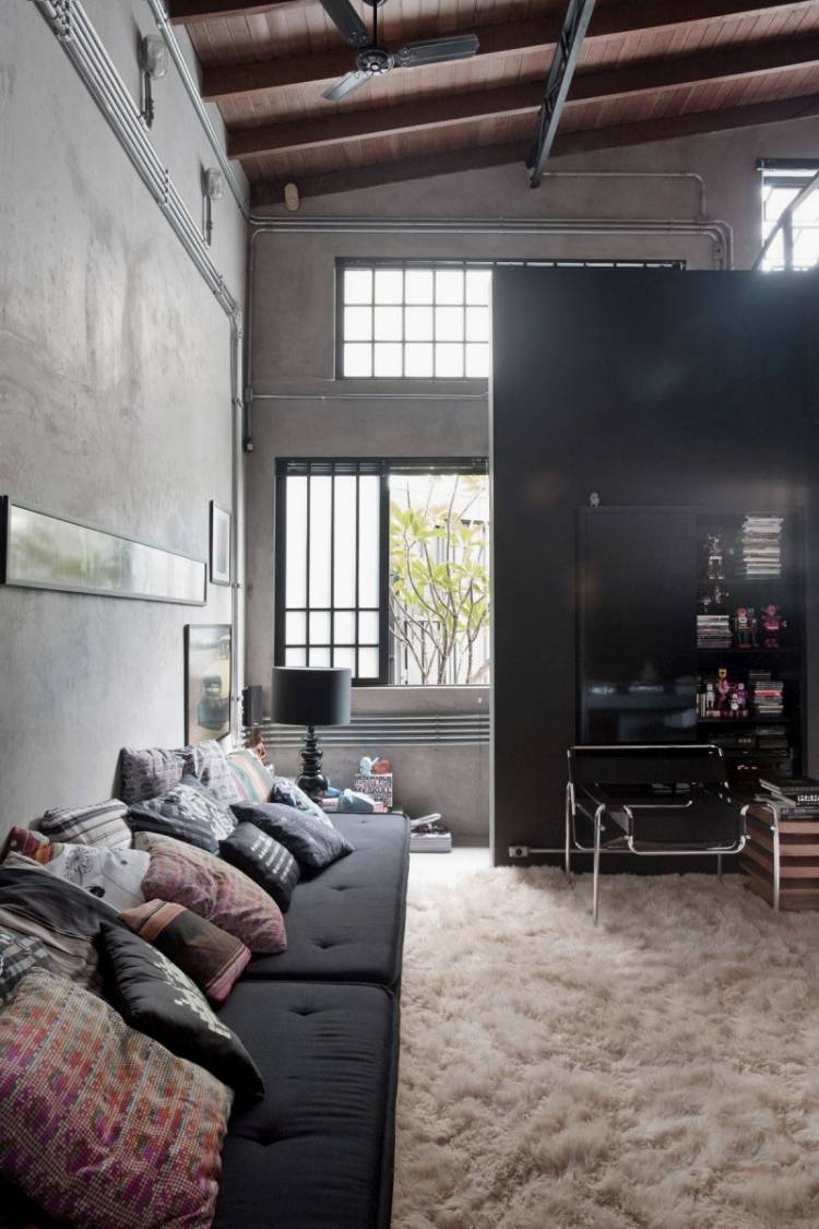 mobilier-industriel-murs-béton-plafond-haut-bois-tapis-shaggy-canapé-noir mobilier industriel
