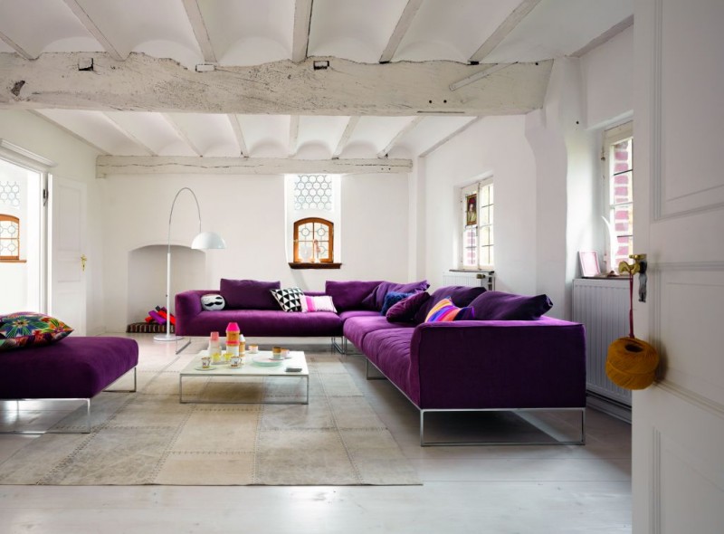 salon-design-canapé-xxl-pourpre-tapis-patchqork-moderne-lampe-sol-blanche-plafond-rustique