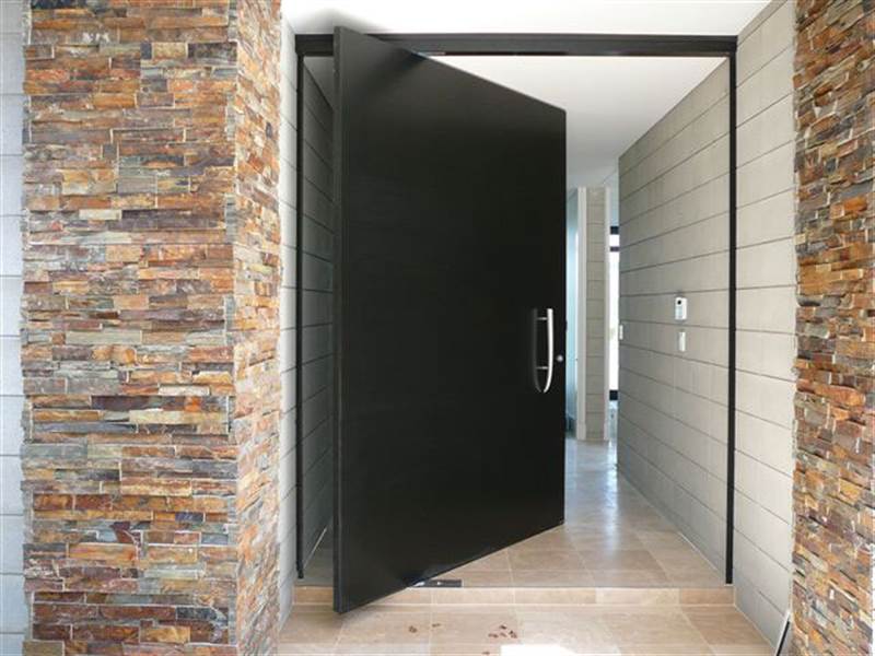 tendances-design-interieur-porte-pivotante-noire-mur-pierre-parement design d’intérieur