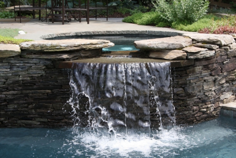 jacuzzi extérieur pierre naturelle cascade piscine