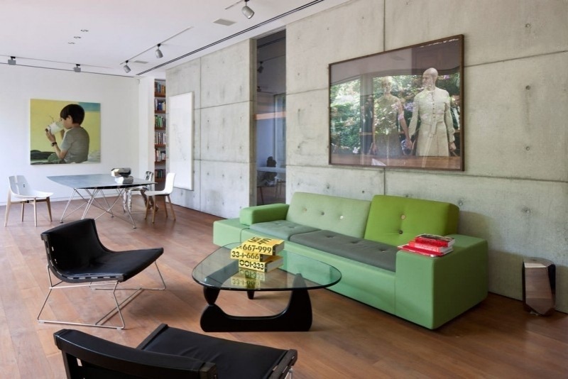 mobilier-beton-mur-béton-canapé-vert-chaises-noires-table-basse-verre-noir mobilier béton