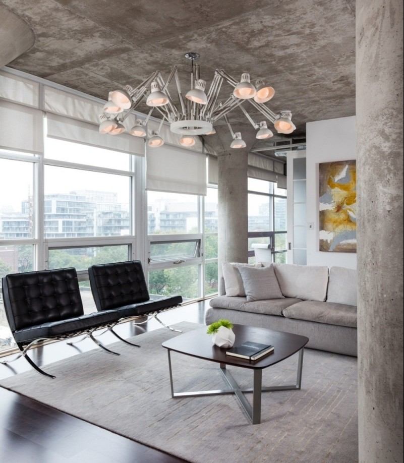 mobilier-beton-plafond-colonnes-béton-canapé-tapis-gris-clair-chaises-cuir-noir