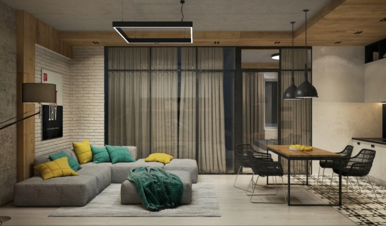 mur-beton-studio-salle-séjour-canapé-gris-ottoman-table-manger-bois-chaises-métal-mur-brique mur béton