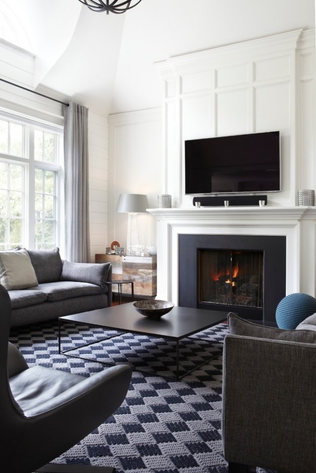 style-masculin-appartement-celibataire-tapis-damier-table-basse-noire-mobilier-gris-cheminée-classique