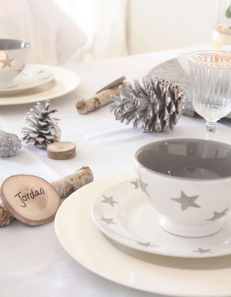 deco-table-Noel-vaisselle-blanche-motifs-étoiles-grises-cônes-pin-blanchis-rondelles-bois