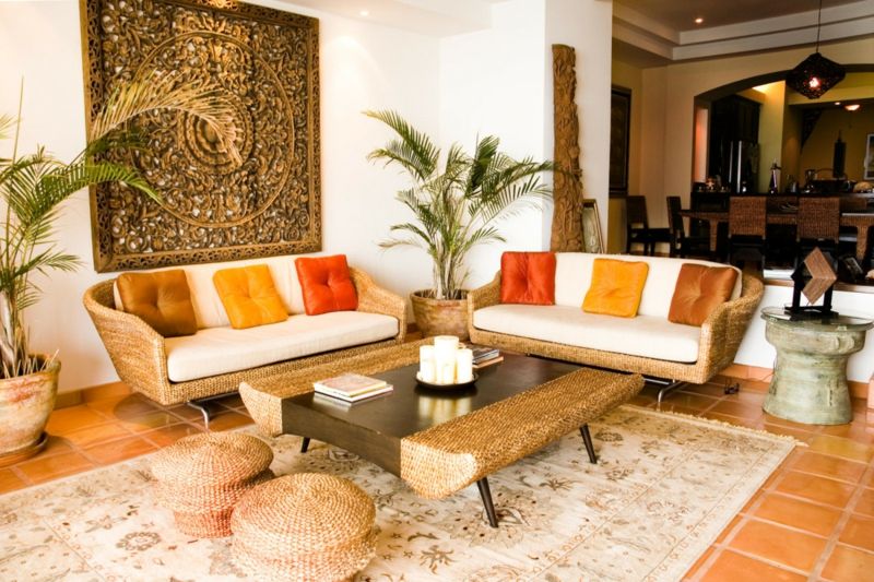 decoration-salon-coussins-orange-jaune-canapés-rotin-palmiers-tableau-exotique
