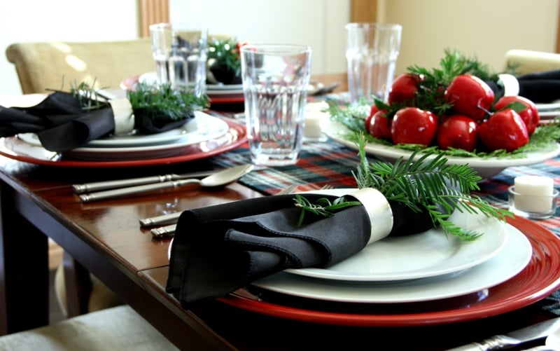 decoration-table-Noel-pommes-rouges-décoratives-seriettes-noires-banhes-sapin