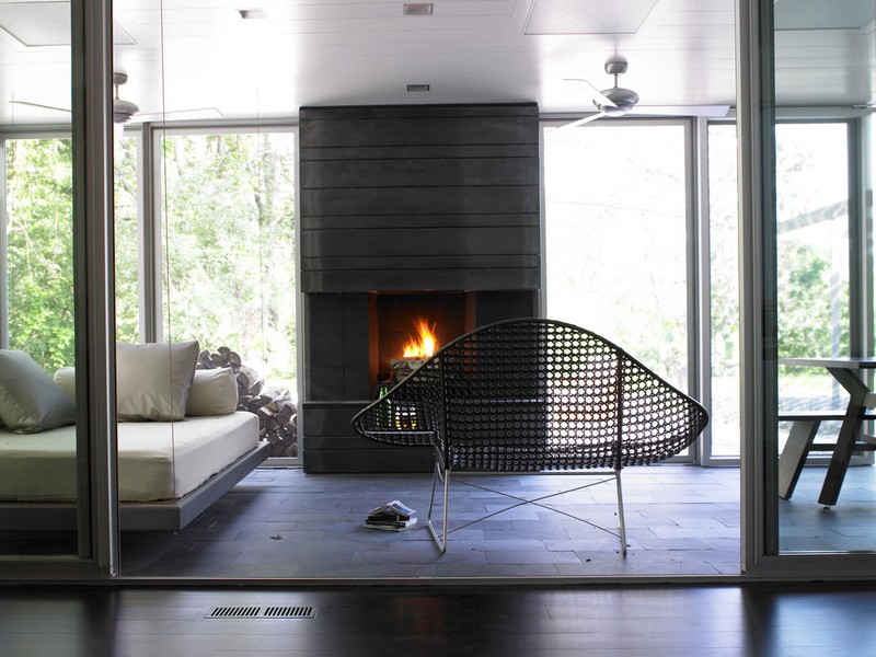 amenagement-veranda-moderne-lit-jour-cheminne-noire-chaise-metal-perfore véranda moderne