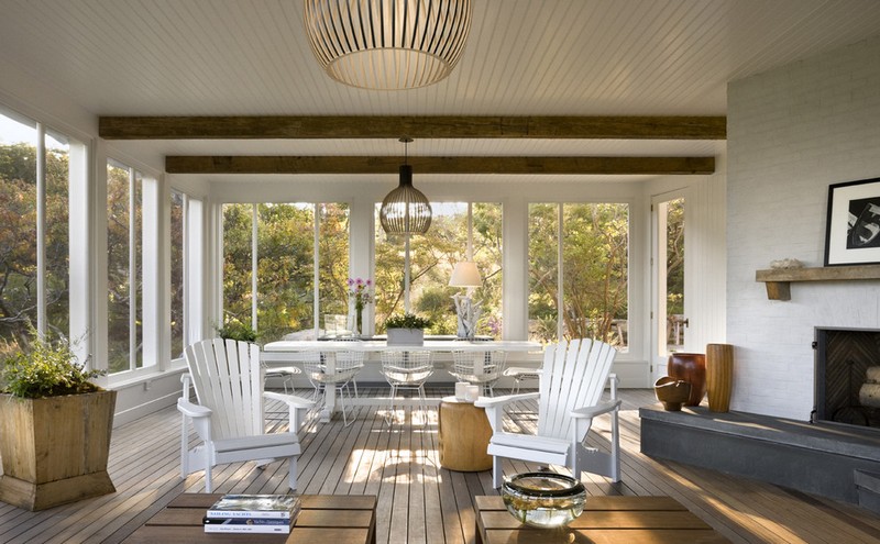 amenagement-veranda-moderne-plafond-bois-blanc-poutres-apparentes-cheminee-brique-blanche-chaises-bois-metal