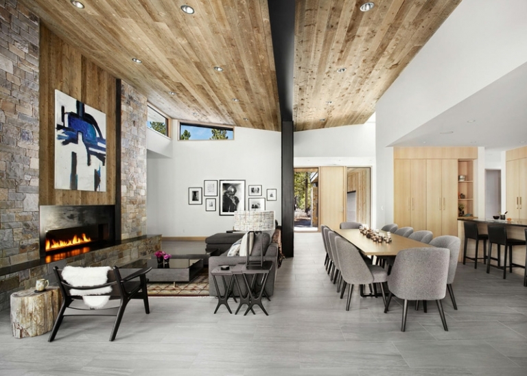 mur-pierre-plafond-papillon-bois-cheminee-moderne-chaises-canape-gris-meubles-bois mur en pierre