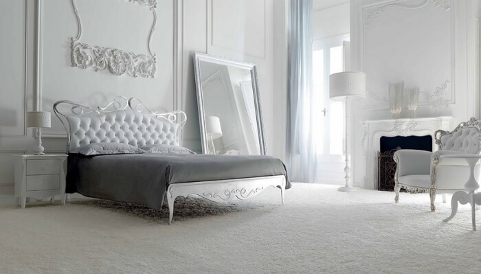 style Art déco chambre-coucher-tete-lit-capitonnee-mur-moulures-fauteuil-blanc-capitonne-cheminee-blanche