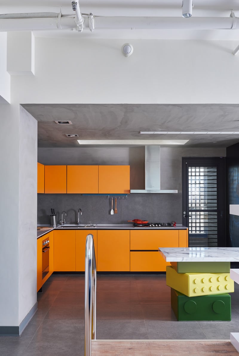 maison-lego-cuisine-L-armoires-orange-murs-plafond-béton