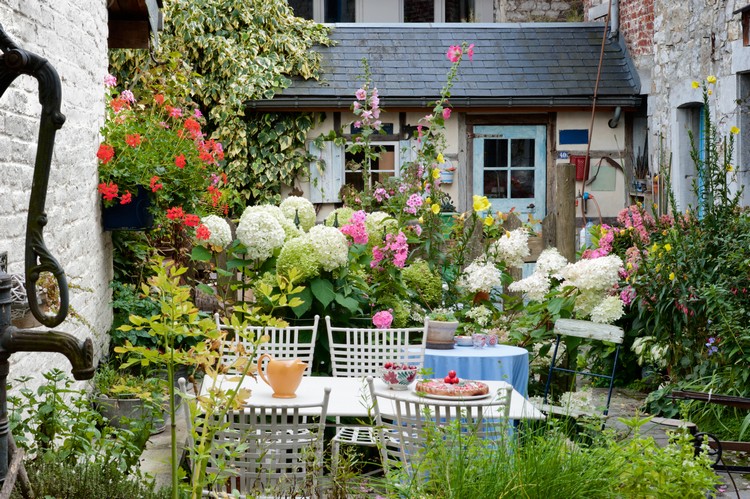 aménagement cour intérieure -table-chaises-blanches-hortensias-petunias