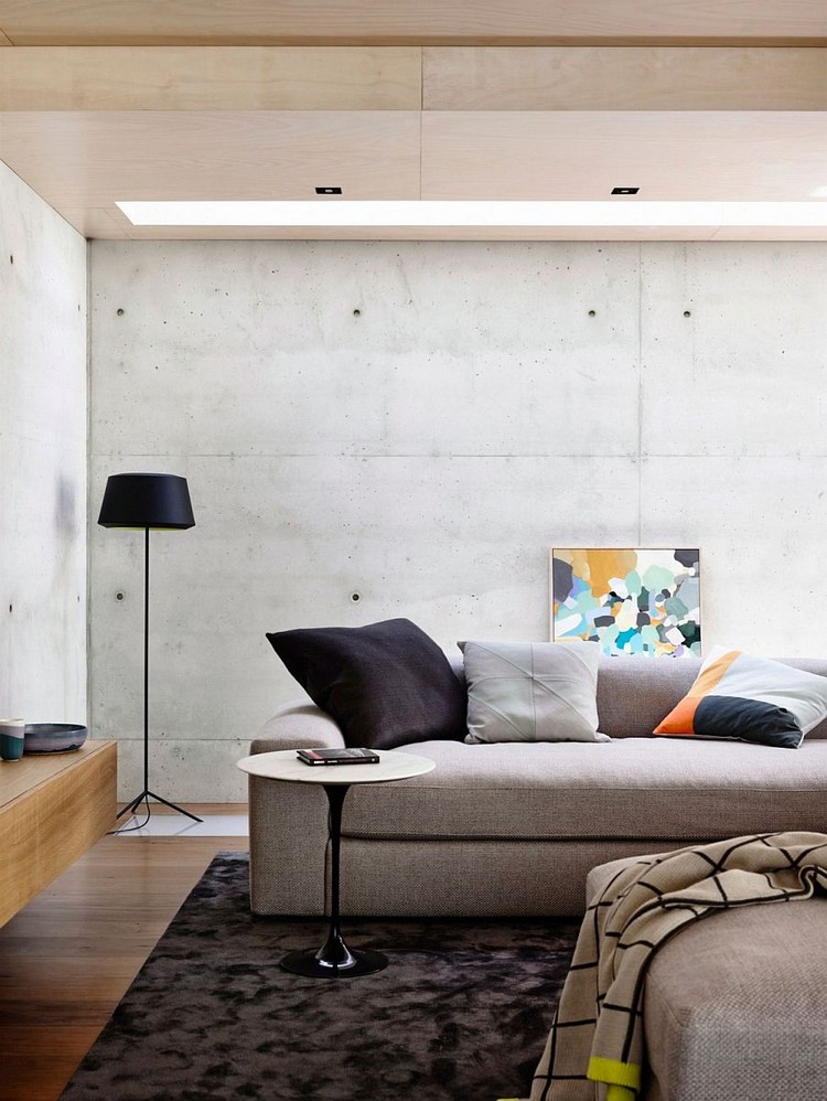 mur en béton banché -salon-canape-gris-lampadaire-noir-plafond-bois