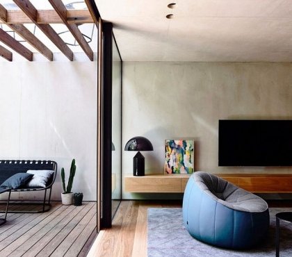 mur en béton banché -salon-tapis-bleu-fauteuil-gris-bleu-meuble-tv-bois-terrasse