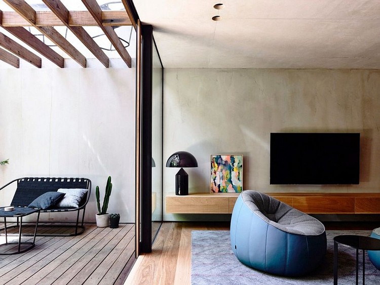 mur en béton banché -salon-tapis-bleu-fauteuil-gris-bleu-meuble-tv-bois-terrasse