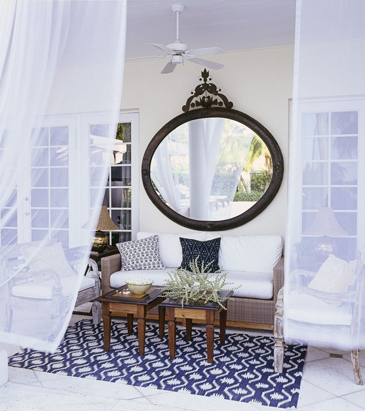 tapis d’extérieur -blanc-bleu-canape-rotin-coussins-noir-blanc-miroir-mural-rond-terrasse