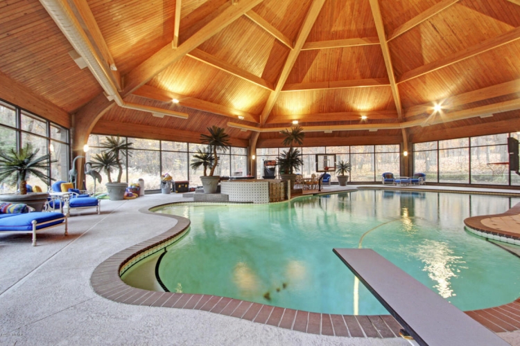 grande-piscine-intérieure-forme-asymétrique-plafond-bois-meubles