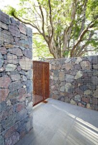 mur-gabion-moderne-grands-blocs-pierre-grise-porte-jardin-acier-corten