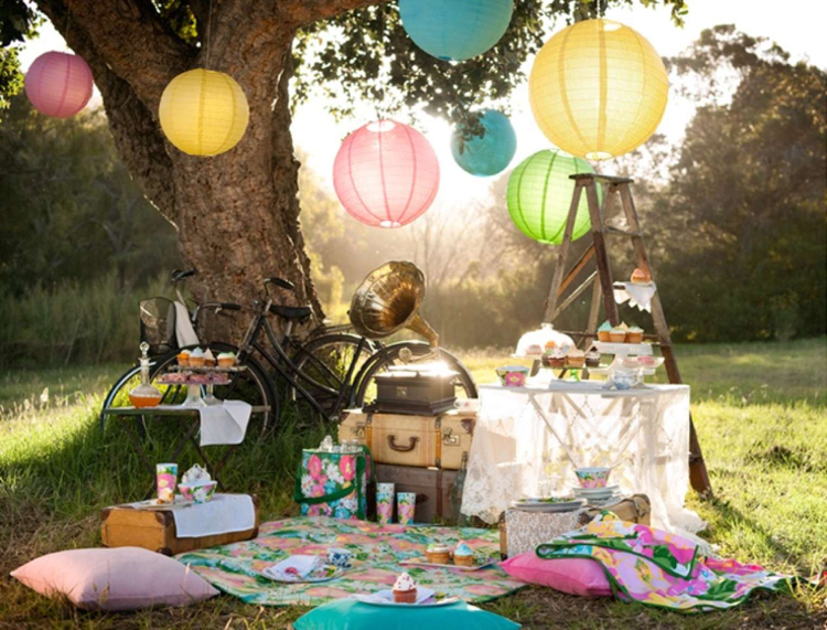 aire de pique-nique –jardin-couverture-motif-floral-coussins-sol-lanternes-papier-cupcakes